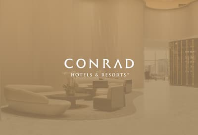Atrium of the Conrad Washington with Conrad Hotels & Resorts logo layered over the image