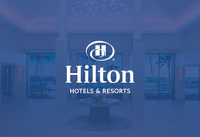 A hotel lobby with the Hilton Hotels & Resorts logo over the top o0f the image