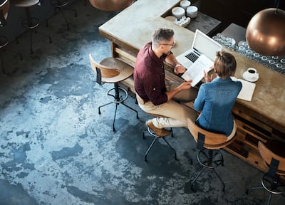 A bird's eye view of a man and a woman sitting at a coffee bar discussing business